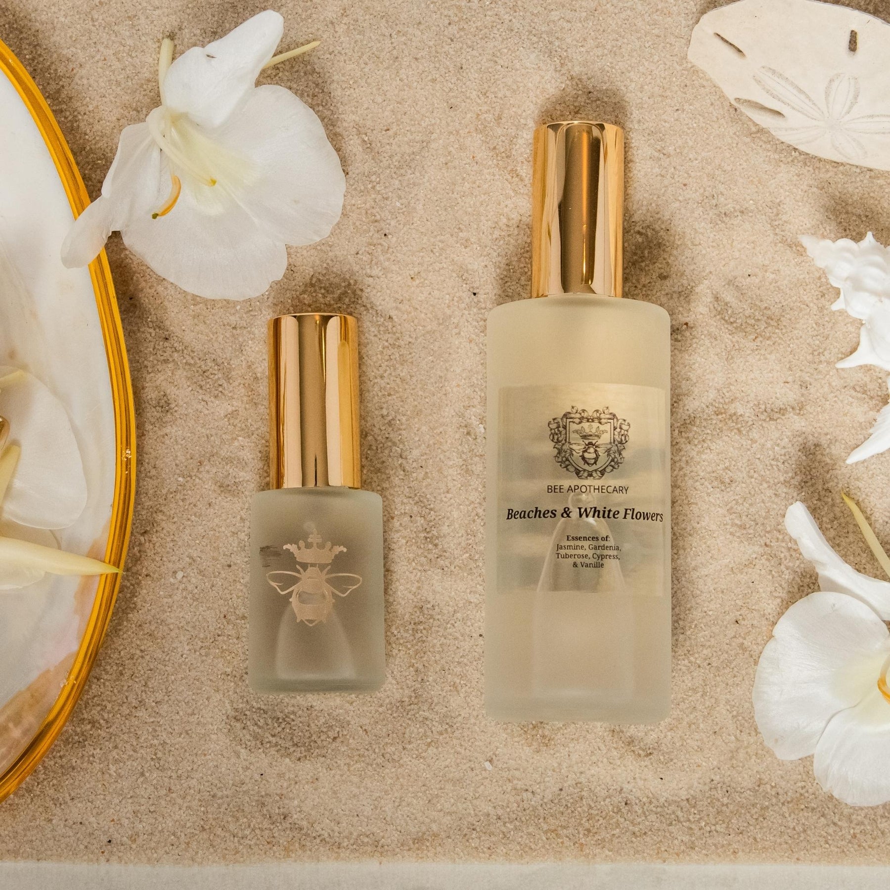 Beaches & White Flowers perfume bottles in the sand by Bee Apothecary